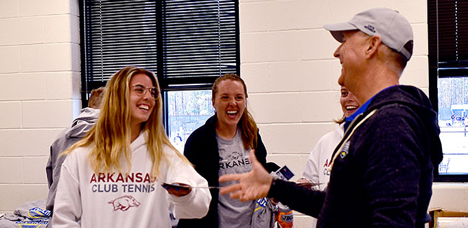 Dave Neuhart hands out a brochure to Katie Cooper. Also pictured is in the middle is Hannah Nixon, co-president of the University of Arkansas team